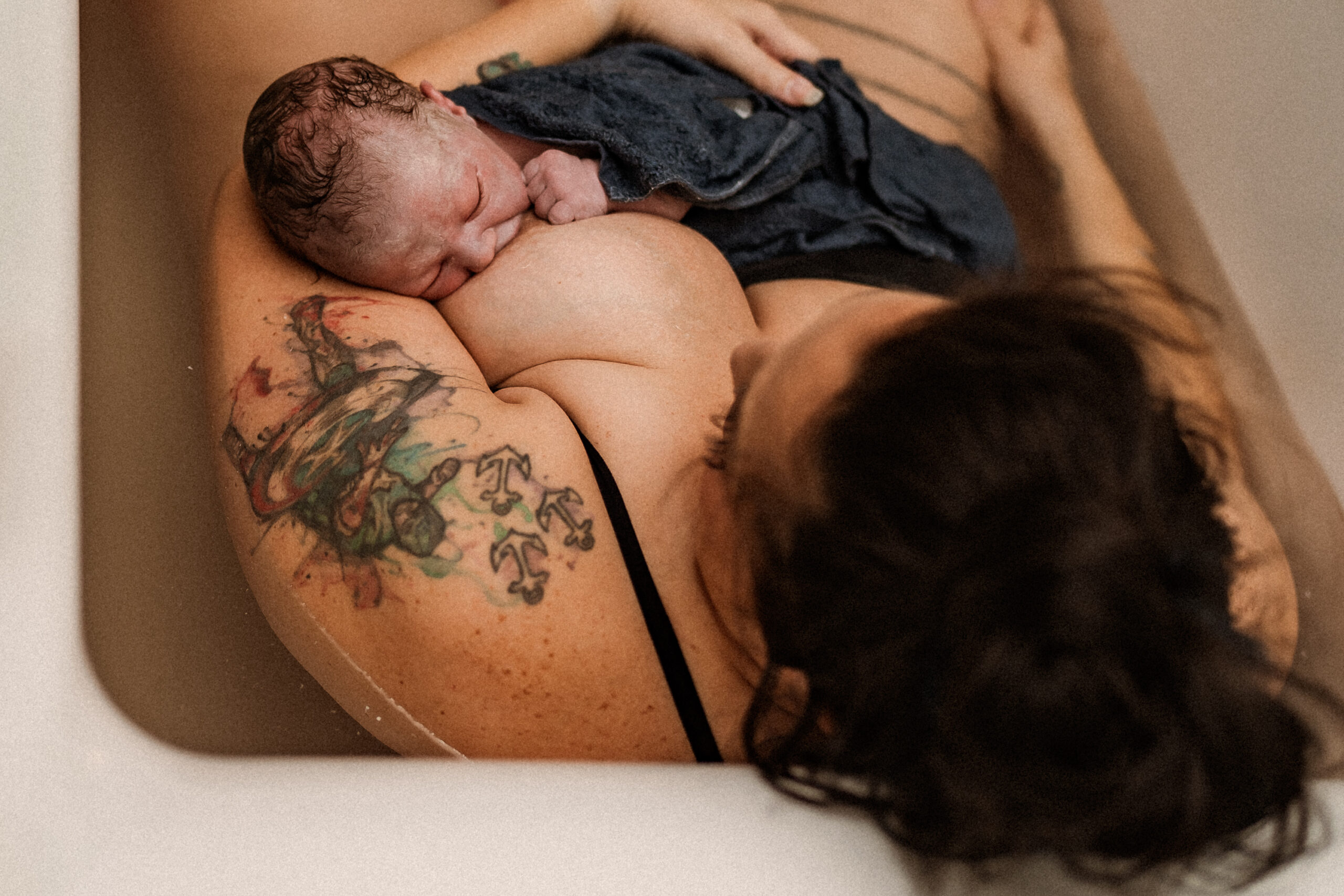 The image shows a mother relaxing and breastfeeding her baby during birth